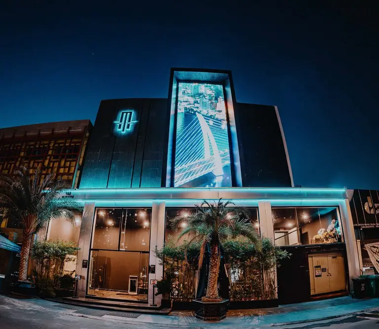 Mặt tiền APLUS SAIGON tại 492 Võ Văn Kiệt, Quận 1 về đêm với màn LED dọc và logo phát sáng